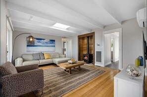 Ein modernes Wohnzimmer mit einer Couch, Sesseln, einem Couchtisch und einem Kamin.