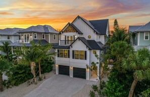 A multi-story residential building with a garage, surrounded by palm trees and other greenery. - Luxury Lido Escape w/ Pool, Slide, Spa & Rooftop! (Sarasota)