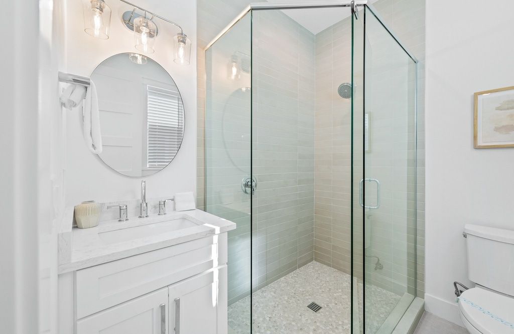 Ein Badezimmer mit Duschkabine, Waschbecken mit Spiegel darüber und Toilette.