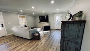Un salon spacieux avec un canapé gris, un téléviseur à écran plat et un plancher en bois.