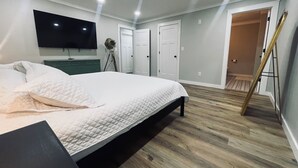 Une chambre à coucher avec un lit, un téléviseur fixé au mur et une lampe sur pied.