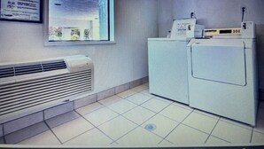 A laundry room with a washing machine, dryer, and a vented heater.
