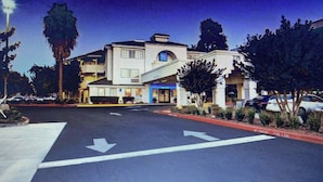 A hotel with a central courtyard, a parking lot, and a street view.