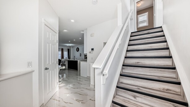 Ein modernes Interieur mit einer Treppe, einer Küchenzeile und einem Flur zu einer Tür.