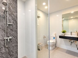 Une salle de bain moderne avec une douche à parois de verre, des toilettes et un lavabo surmonté d’un miroir.