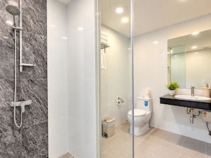 Een moderne badkamer met een douchecabine, een toilet en een wastafel met spiegel.