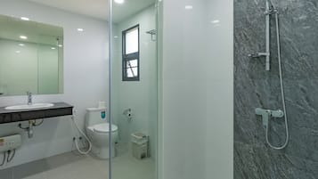 A modern bathroom with a glass-enclosed shower, a white sink, and a toilet.