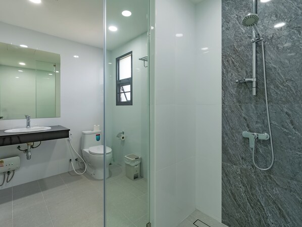 Une salle de bain moderne avec une douche à parois de verre, un lavabo blanc et des toilettes.