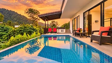 A modern outdoor pool area with a clear view of the surrounding greenery and hills.