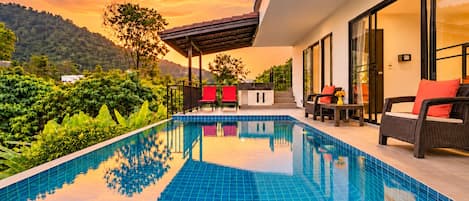 A modern outdoor pool area with a clear view of the surrounding greenery and hills.
