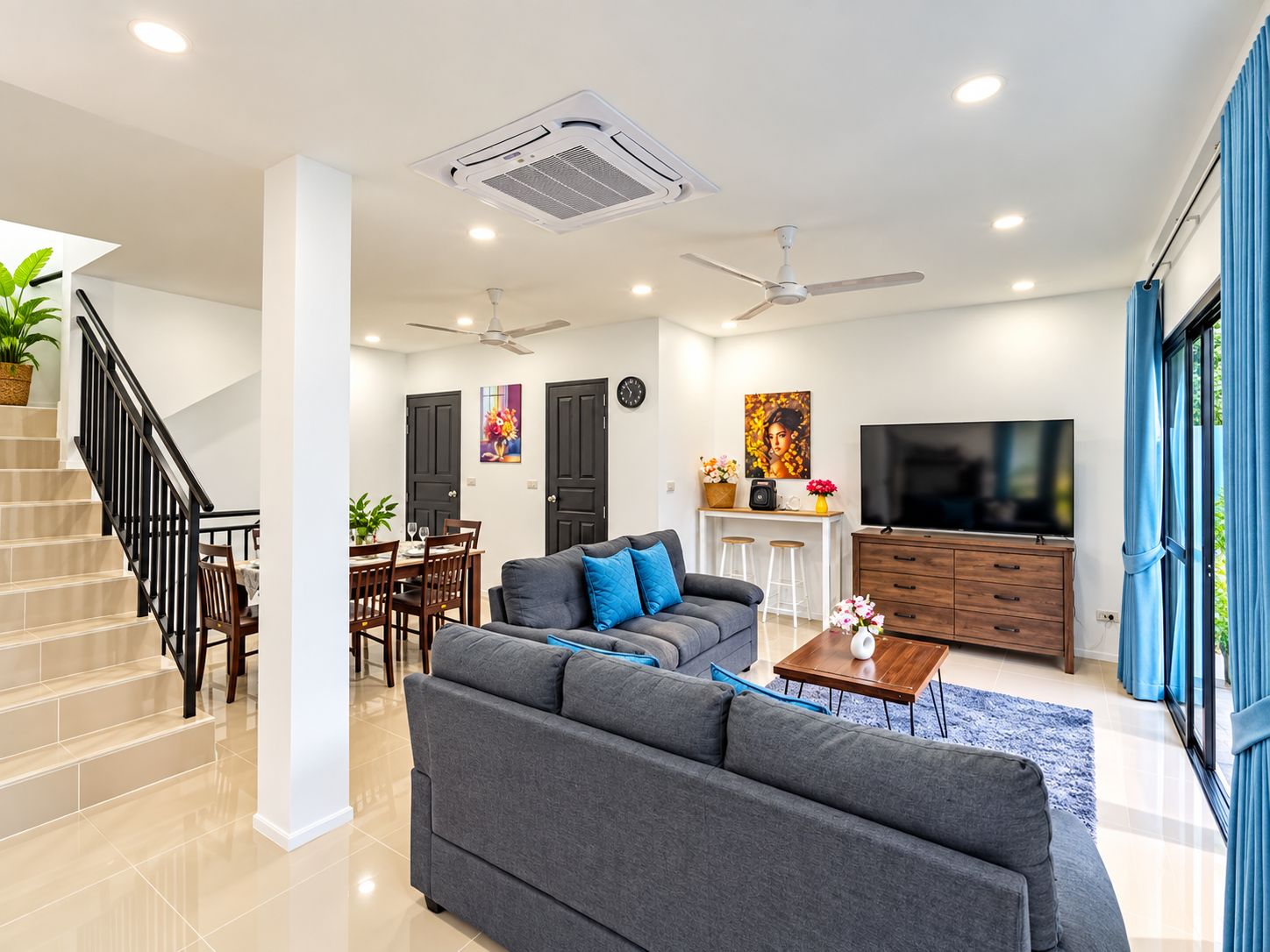 A modern living room with a sofa, a TV, and a staircase.