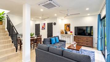 Un salon moderne avec un canapé, un téléviseur et un escalier.