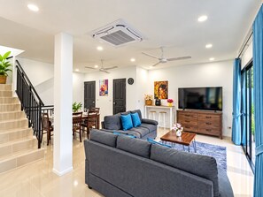 Un salon moderne avec un canapé, un téléviseur et un escalier.