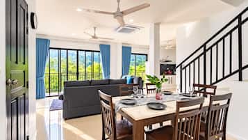 A modern interior with a dining area, sofa, and staircase.