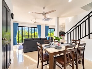 A modern interior with a dining area, sofa, and staircase. - Brand New Private Pool Villa Chalong Phuket Mountain View (Chalong)