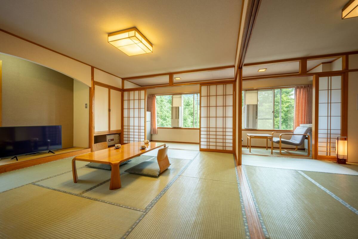 A traditional Japanese room with tatami flooring, a low table, a television, and sliding doors.