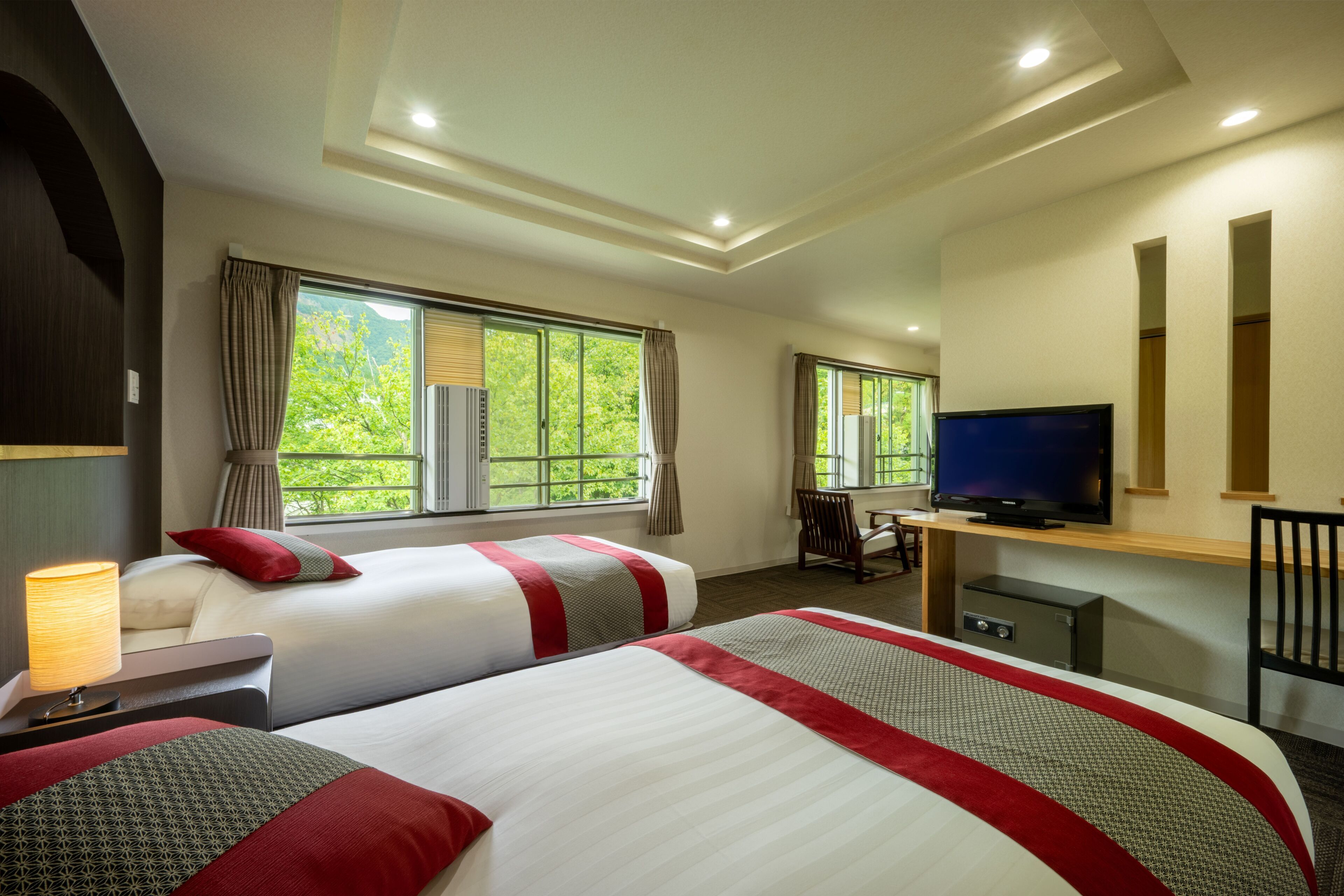 Une chambre d’hôtel avec deux lits, une télévision, un bureau et une chaise.