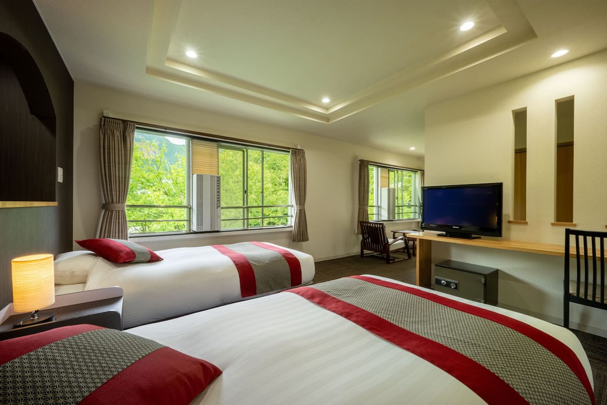 Une chambre d’hôtel avec deux lits, une télévision, un bureau et une chaise.