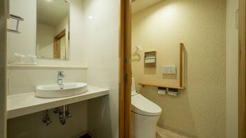 A modern bathroom with a sink, mirror, toilet, and shower area.