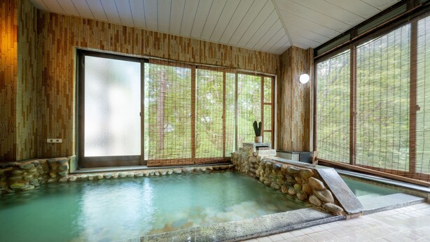 A traditional Japanese onsen with a stone bath, wooden walls, and large windows. - KKR Zao Hakuginso (Yamagata)