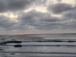 A beach with waves and a cloudy sky.