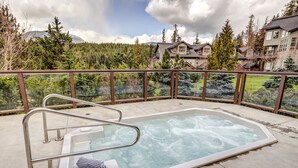 Ein Whirlpool auf einem Balkon mit Blick auf einen Wald und Häuser.