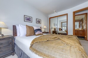 A hotel room with a bed, bedside tables, a mirror, and framed pictures on the wall. - Blackcomb Greens #4 - Mountain View, Right on the Golf Course! (Whistler)