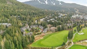 Eine gebirgige Landschaft mit einem Wohngebiet, das Häuser und einen Golfplatz zeigt.