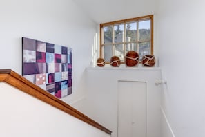 Un escalier avec une rampe en bois, une porte blanche et une fenêtre donnant sur des arbres.