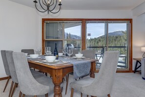 A dining room with a wooden table set for four, surrounded by grey upholstered chairs. - Blackcomb Greens #4 - Mountain View, Right on the Golf Course! (Whistler)