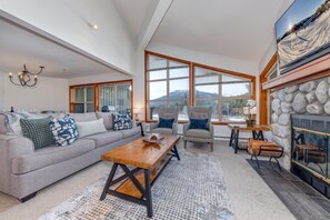 A spacious living room with a large window, a fireplace, and a cozy seating area. - Blackcomb Greens #4 - New Listing, Mountain View, Right on the Golf Course! (Whistler)