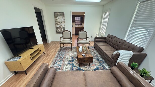A living room with a flat-screen TV, two sofas, a coffee table, and a patterned rug. - Modern 2BR Suite 202: Toledo & Sylvania Gateway (Toledo)