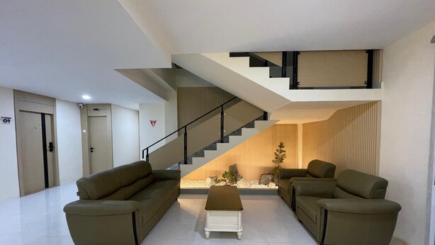 A modern living room with a sofa set, a coffee table, and a staircase leading to an upper level. - Gobah Homestay G-Home Syariah (Pekanbaru)