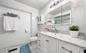 A modern bathroom with a white sink, mirror, and toilet.