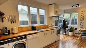 Une cuisine moderne avec un plancher en bois, un lave-linge encastré, un évier et une cuisinière.