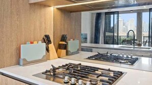 A modern kitchen with a built-in gas stove, oven, and a large window offering a city view. - Level 10 Views | 2BR with Private Balcony & Parking (Brisbane)