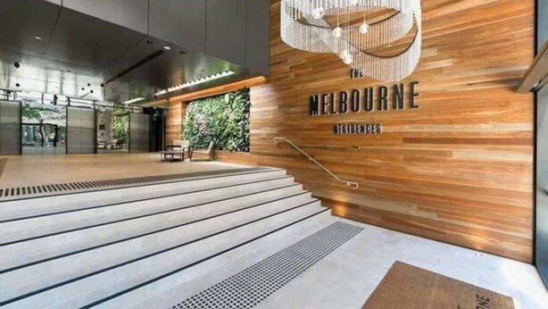 A modern hotel lobby with a wooden wall, a chandelier, and a staircase. - Level 10 Views | 2BR with Private Balcony & Parking (Brisbane)