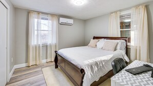 Une chambre avec un lit en bois, un bureau avec une chaise et un appareil de climatisation fixé au mur.