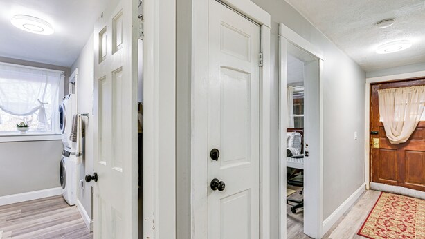 Un couloir avec des portes blanches, un espace dédié à la buanderie et une porte en bois avec un rideau.