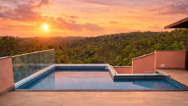 Una piscina en la azotea con vistas a la puesta de sol sobre un paisaje boscoso.