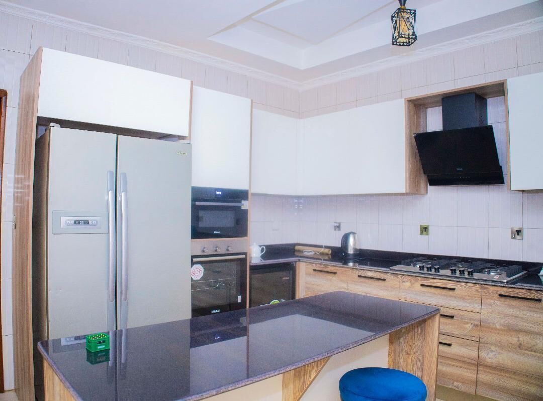 A modern kitchen with a refrigerator, oven, stove, and wooden cabinets.
