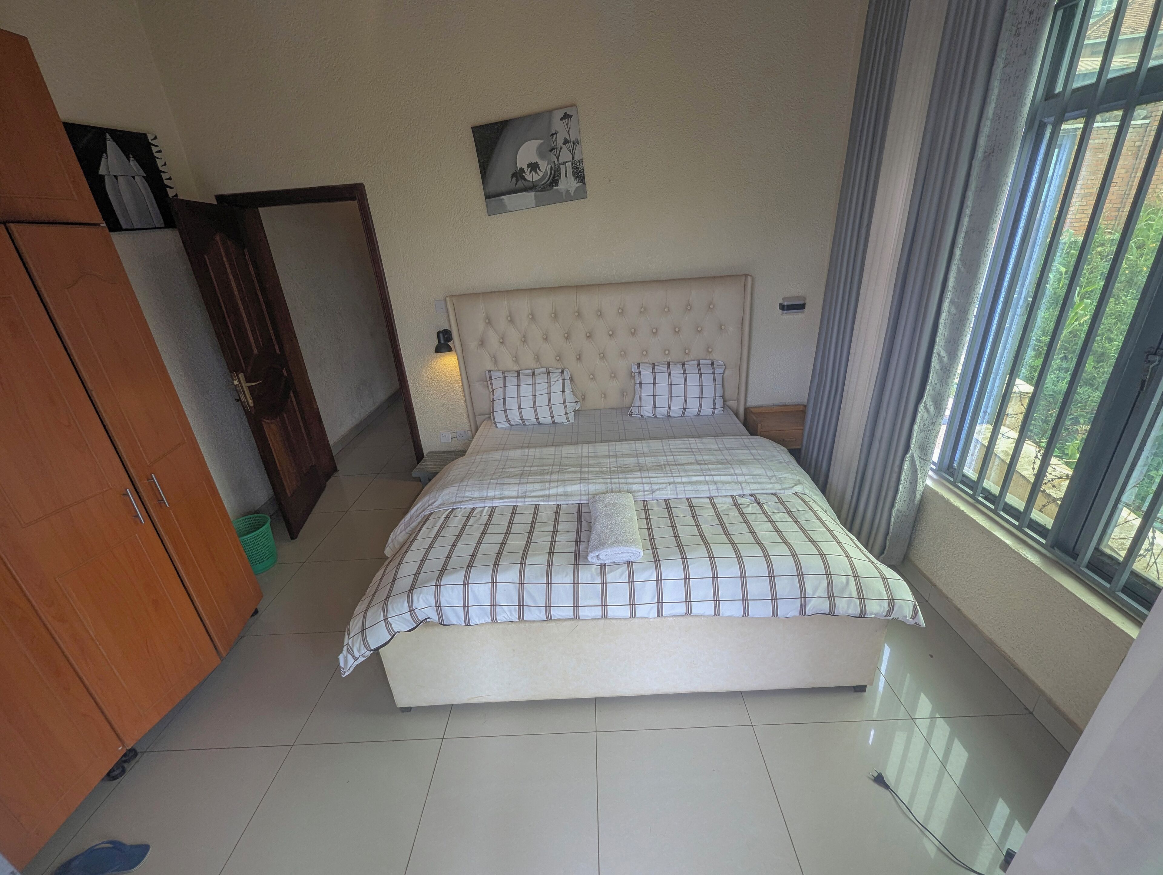 Une chambre bien rangée, avec un lit, une armoire et une fenêtre avec des rideaux.