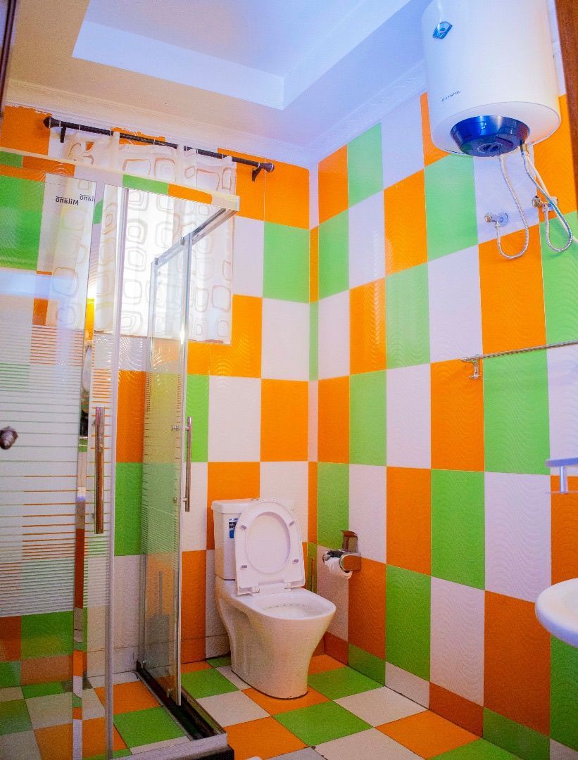 Een badkamer met een zwart-wit geruit tegelpatroon, een toilet, een douche en een wastafel.
