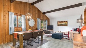 A wooden interior with a dining area, a sofa, and a TV.