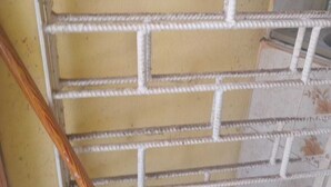 Un escalier avec un mur jaune et une rampe en corde blanche.