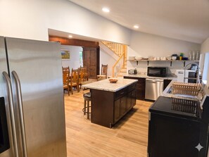 A modern kitchen with a central island, wooden dining table, and built-in appliances.