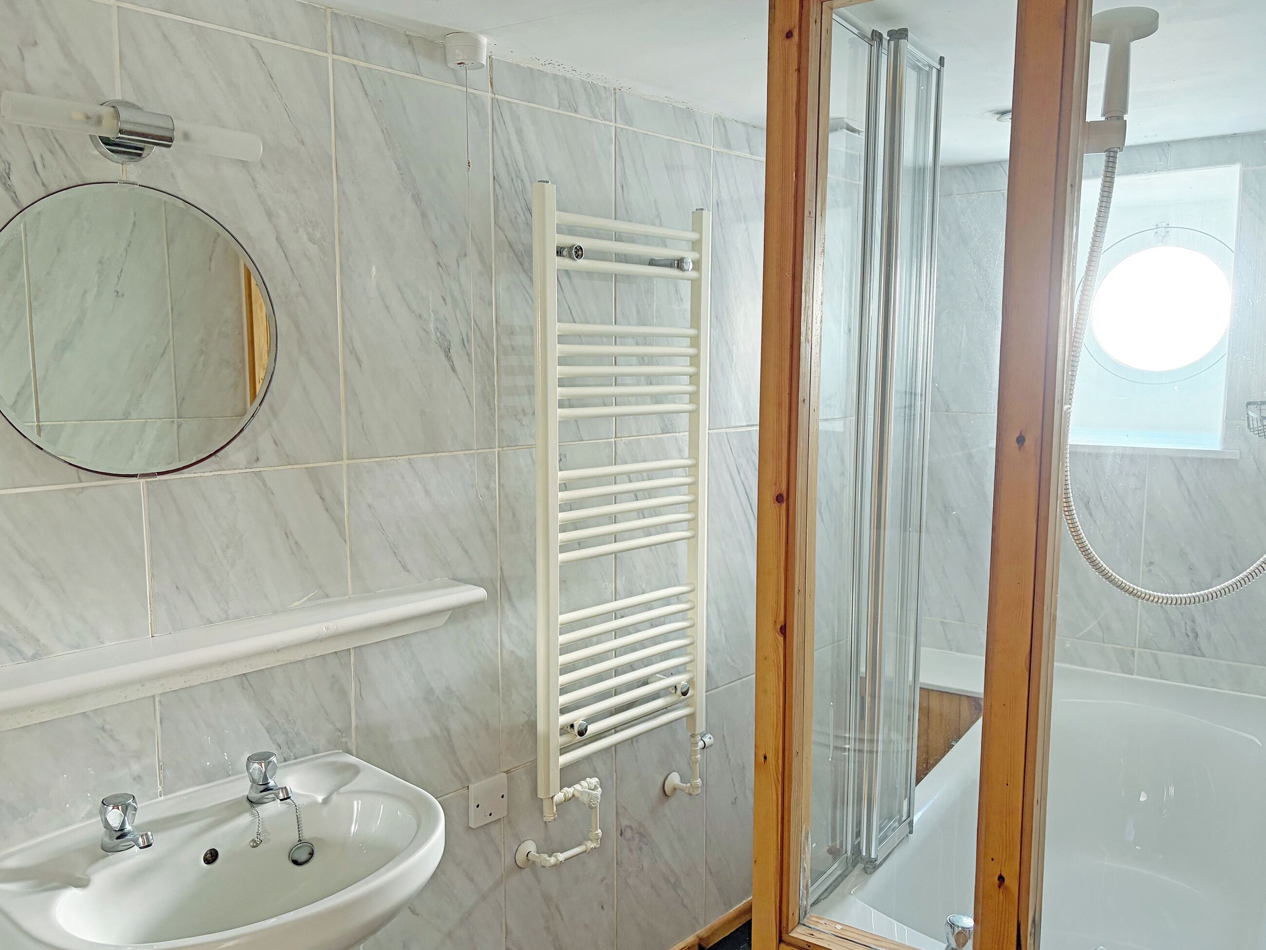 Un baño con lavamanos, espejo, toallero, cabina de ducha y bañera.