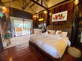 Quarto espaçoso com cama grande, piso de madeira, varanda com vista e uma pintura na parede.