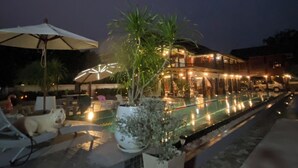 A poolside area with a lounge chair, a large umbrella, and a potted plant. - The Elephant House and Pool Villas (San Pa Thong)