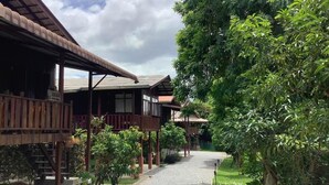 A traditional wooden building with a covered walkway and a gravel path leading through a lush garden. - The Elephant House and Pool Villas (San Pa Thong)
